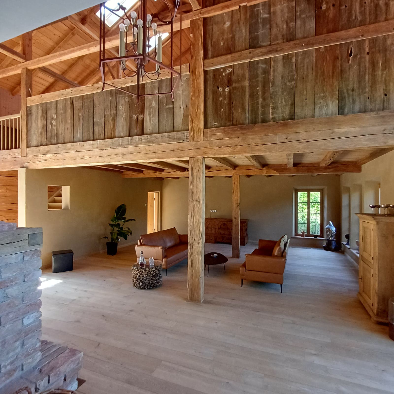 Living space with clay plaster, a beamed ceiling and two leather sofas
