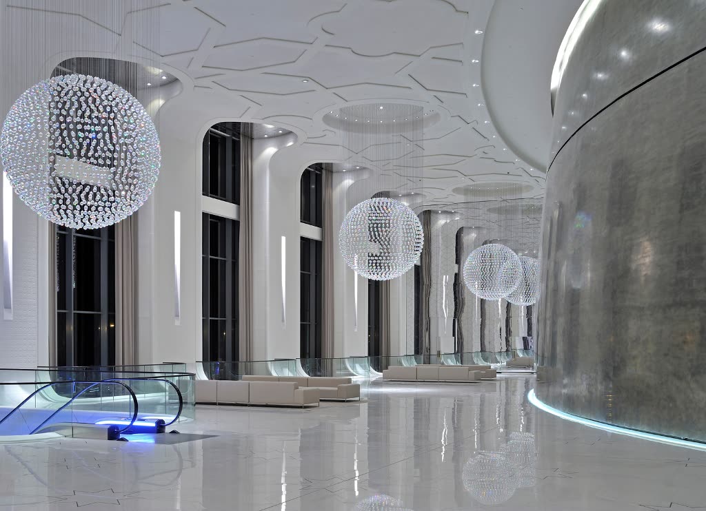 Lobby in a commercial project with a metallic trowelled curved wall and chandeliers