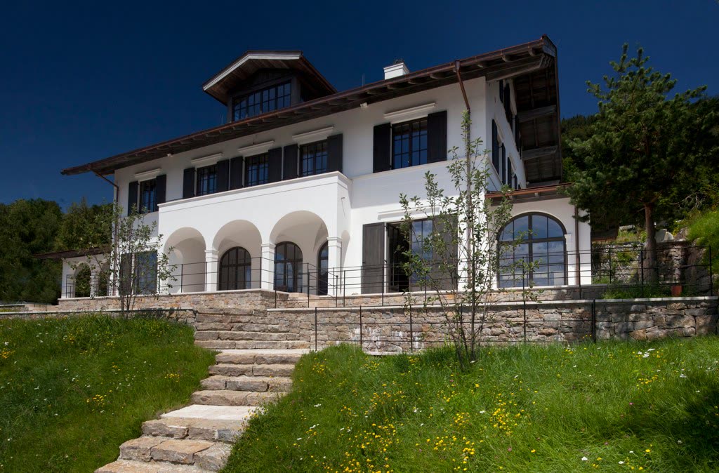 Villa with a white rendered facade and arches, seen from the garden