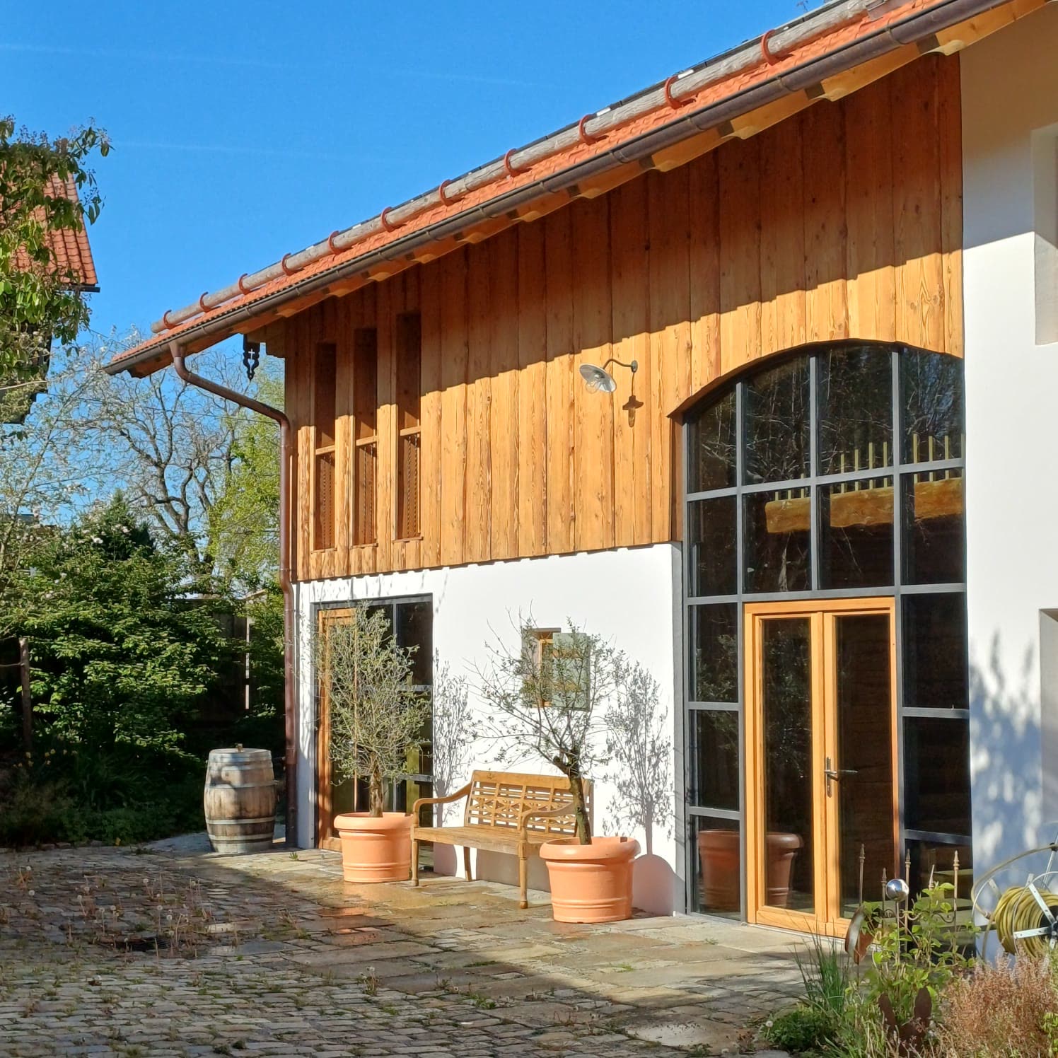 Renovated country house with a timber facade and an arched window