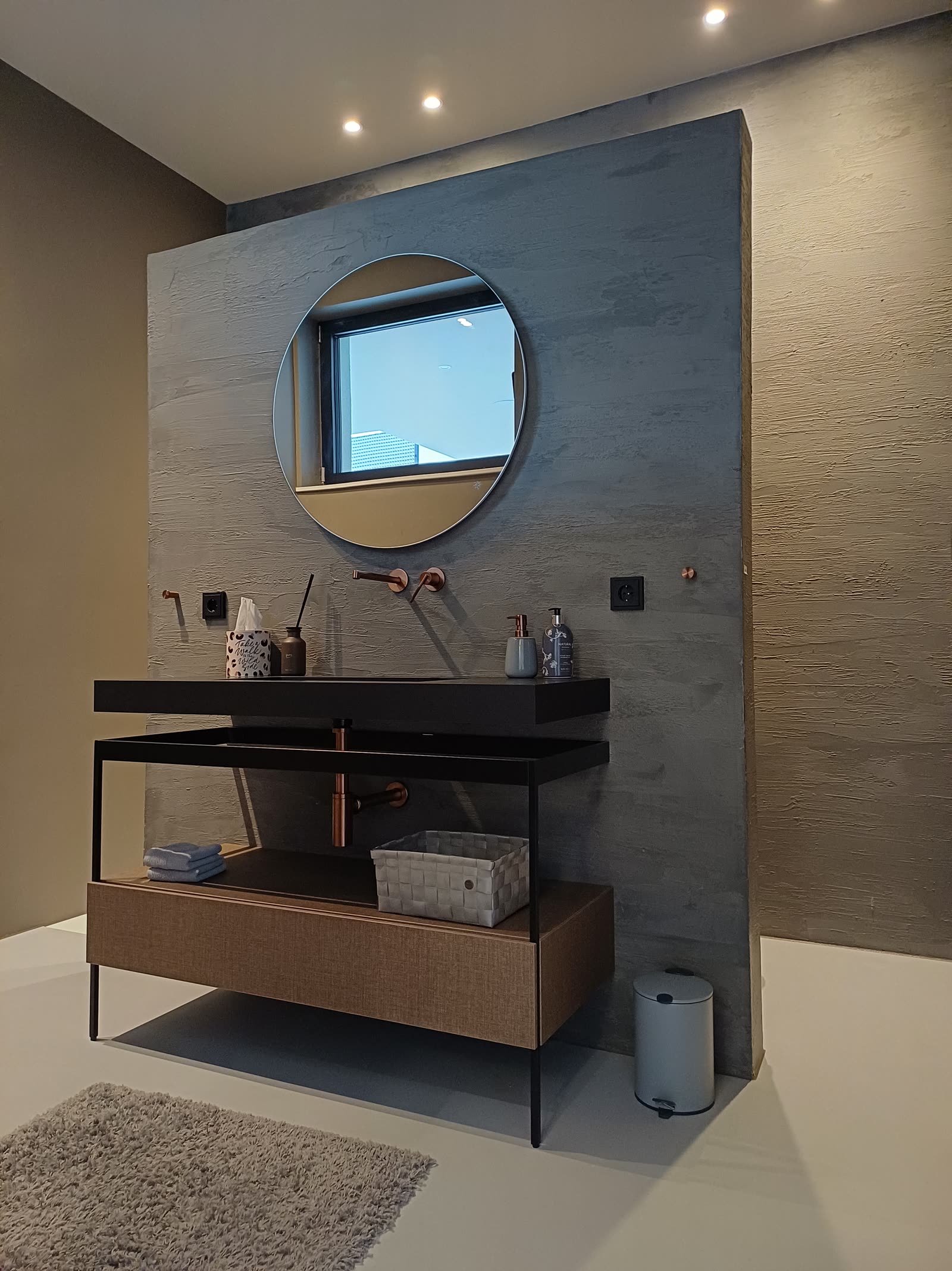 Trowelled wall in a concrete look with a round mirror