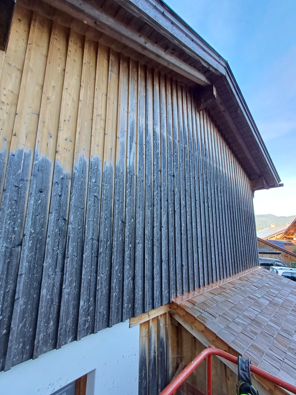 Timber facade during dry-ice blasting: cleaned at the top, still weathered below