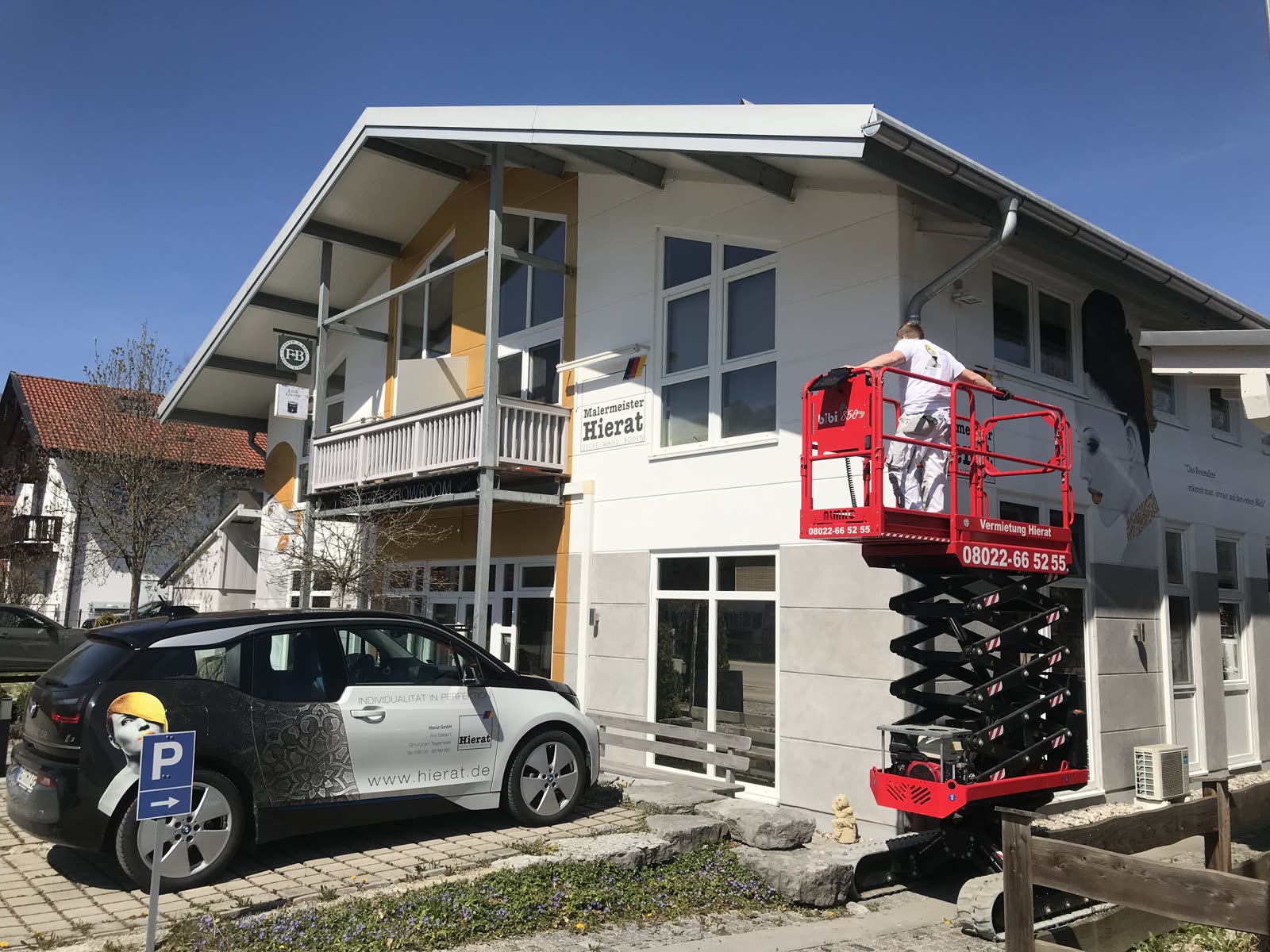 Business premises of Hierat, master painters, with company vans and an aerial work platform